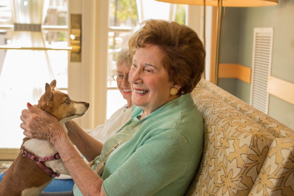 Two female residents smiling holding a dog